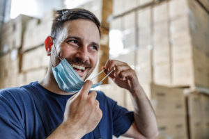 Warehouse Worker Smiling and putting on a mask
