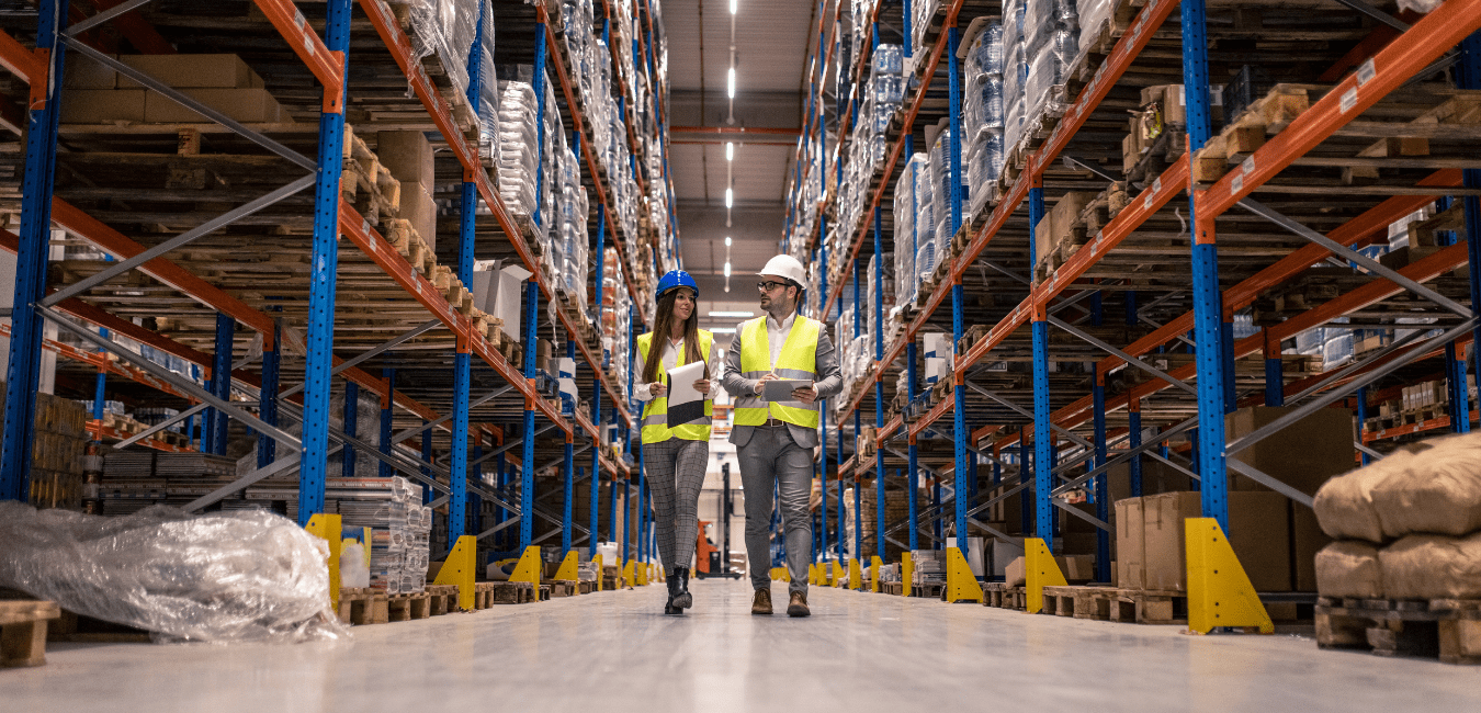 Warehouse workers walking down aisle of warehouse taking inventory